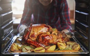 Man roasting a turkey in the oven.