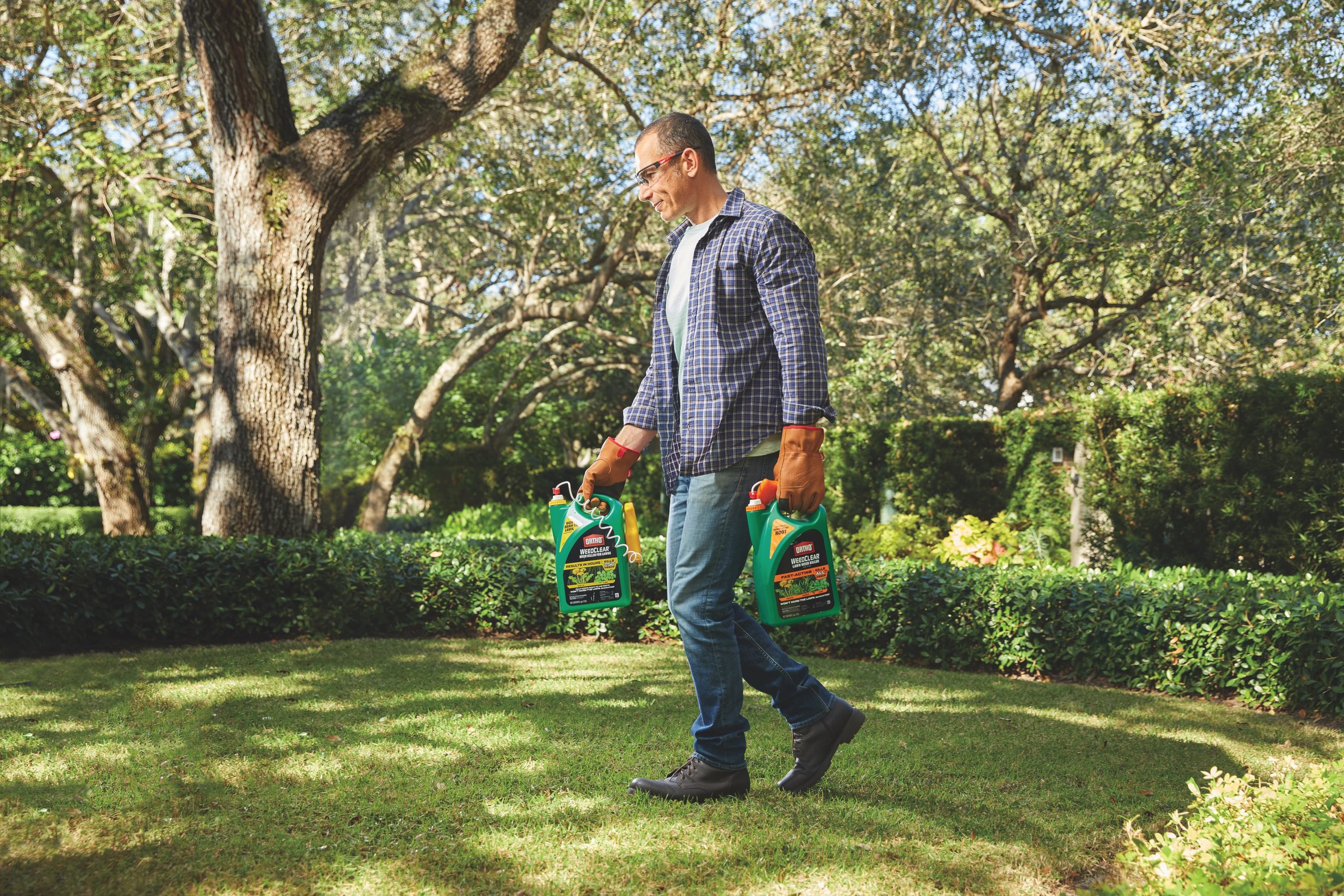 Man walking on lawn while holding insecticide.